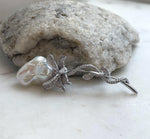 Elegant white pearl brooch with delicate vine details and sparkling crystal accents.