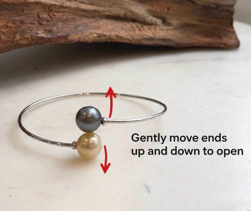 Platinum gray and champagne gold ocean pearls with mirror luster on an open silver band.