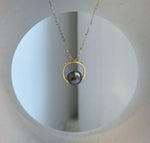 Minimalist pearl necklace with a circular sterling silver pendant and delicate gold-tone chain.
