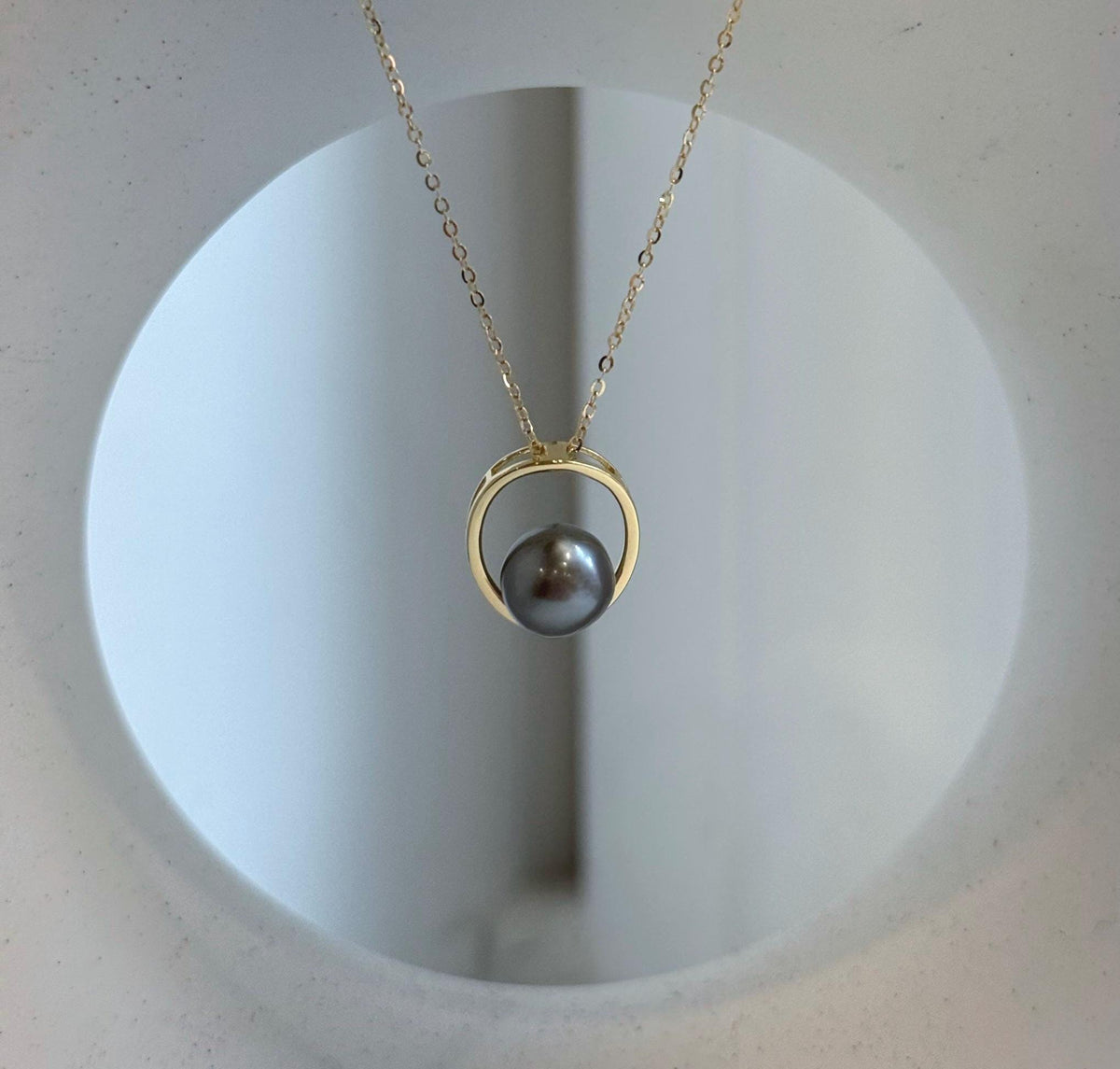 Minimalist pearl necklace with a circular sterling silver pendant and delicate gold-tone chain.
