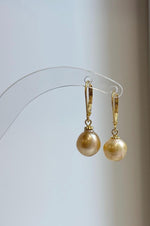 Lustrous champagne pearls hanging beneath small decorative gold-tone caps.
