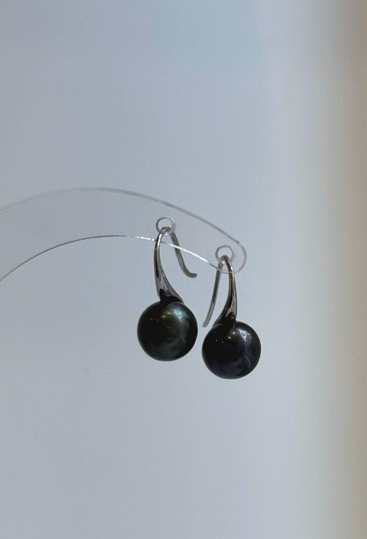 Close-up of glossy dark pearls with green and blue overtones.