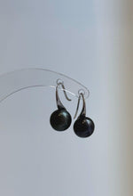 Close-up of glossy dark pearls with green and blue overtones.