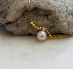 Genuine ivory Akoya pearl paired with gold-tone beads in an adjustable necklace.