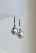 Edison pearl drop earrings with curved sterling silver hooks and fluted pearl caps.
