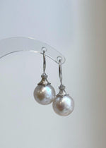 White freshwater pearls reflecting soft pink and blue hues in natural light.