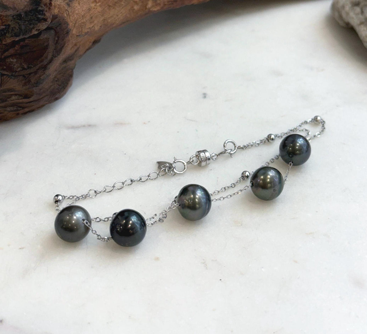 Dark Tahitian pearls linked by fine silver chains with a silver clasp.