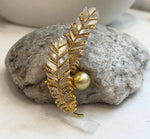 Gold-tone feather jewelry with white iridescent inlays and a golden pearl