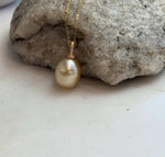 Golden pearl drop pendant displaying mirror luster and subtle color overtones.