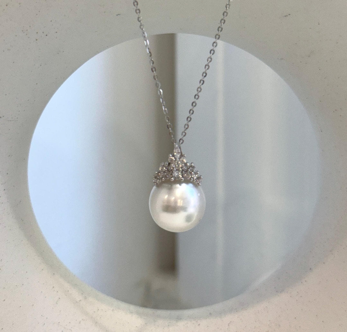 White South Sea pearl crown pendant with a reflective surface and delicate silver detailing.