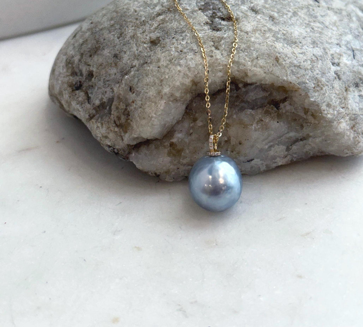 Silver blue ocean pearl pendant with a reflective surface and moissanite detailing in solid gold.