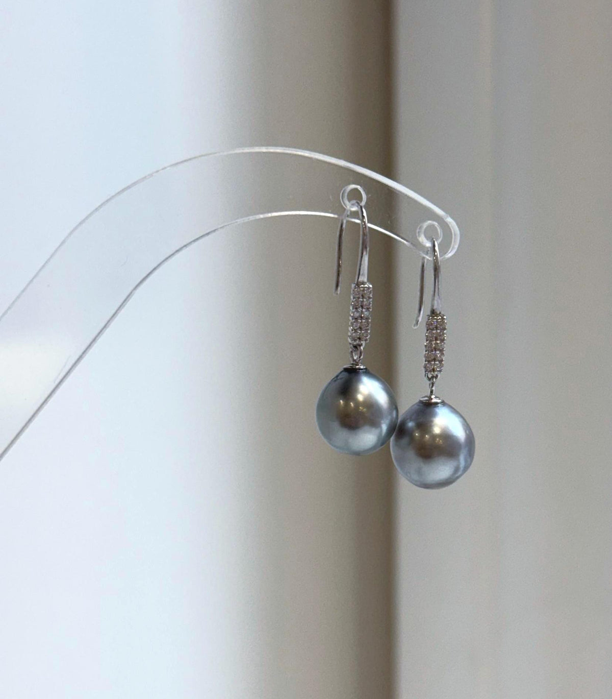Dark silver gray pearl earrings on a clear display