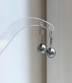 Dark silver gray pearl earrings on a clear display