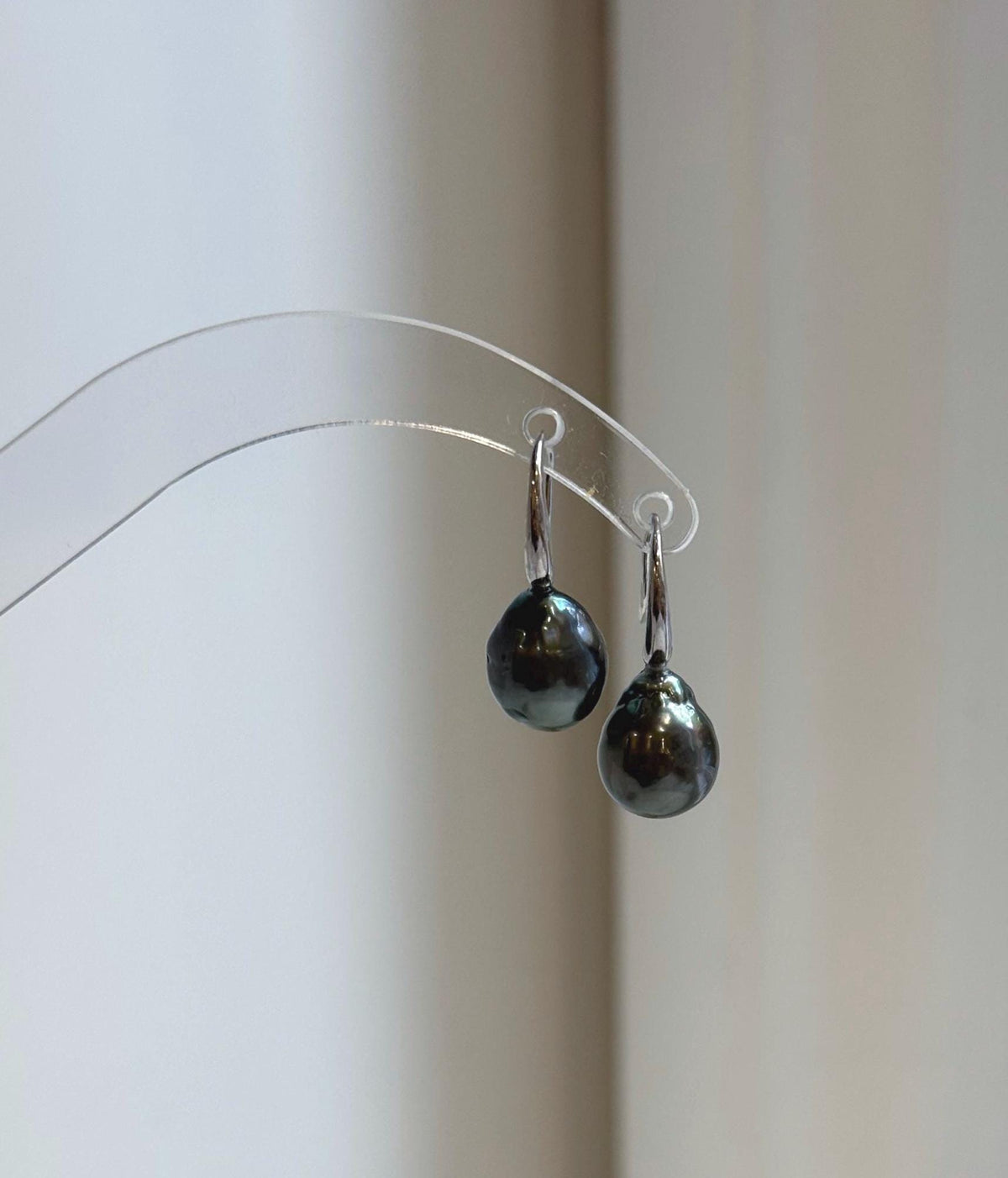 Dark silver gray pearl earrings on a clear display