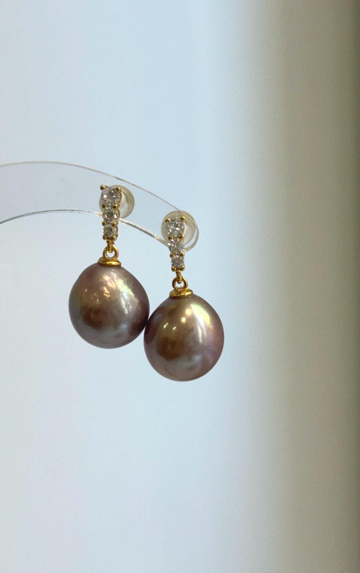 Edison pearl earrings displaying a reflective surface and rose mauve color.