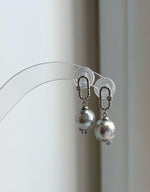 Silver blue Akoya pearl earrings photographed in natural light against a neutral background.
