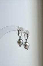 Akoya pearl earrings showing soft pink and green reflections across silver blue surfaces.