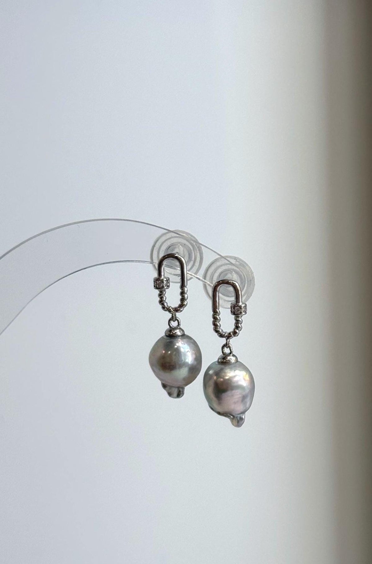 Akoya pearl earrings showing soft pink and green reflections across silver blue surfaces.