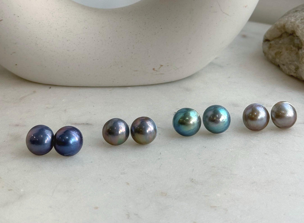 Iridescent Mabe pearl earrings with rounded profiles and reflective luster.