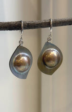 Mabe pearl earrings with mirror luster and rainbow reflections.