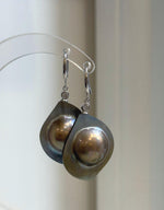 Lustrous golden mabe pearl earrings with shifting rainbow hues.
