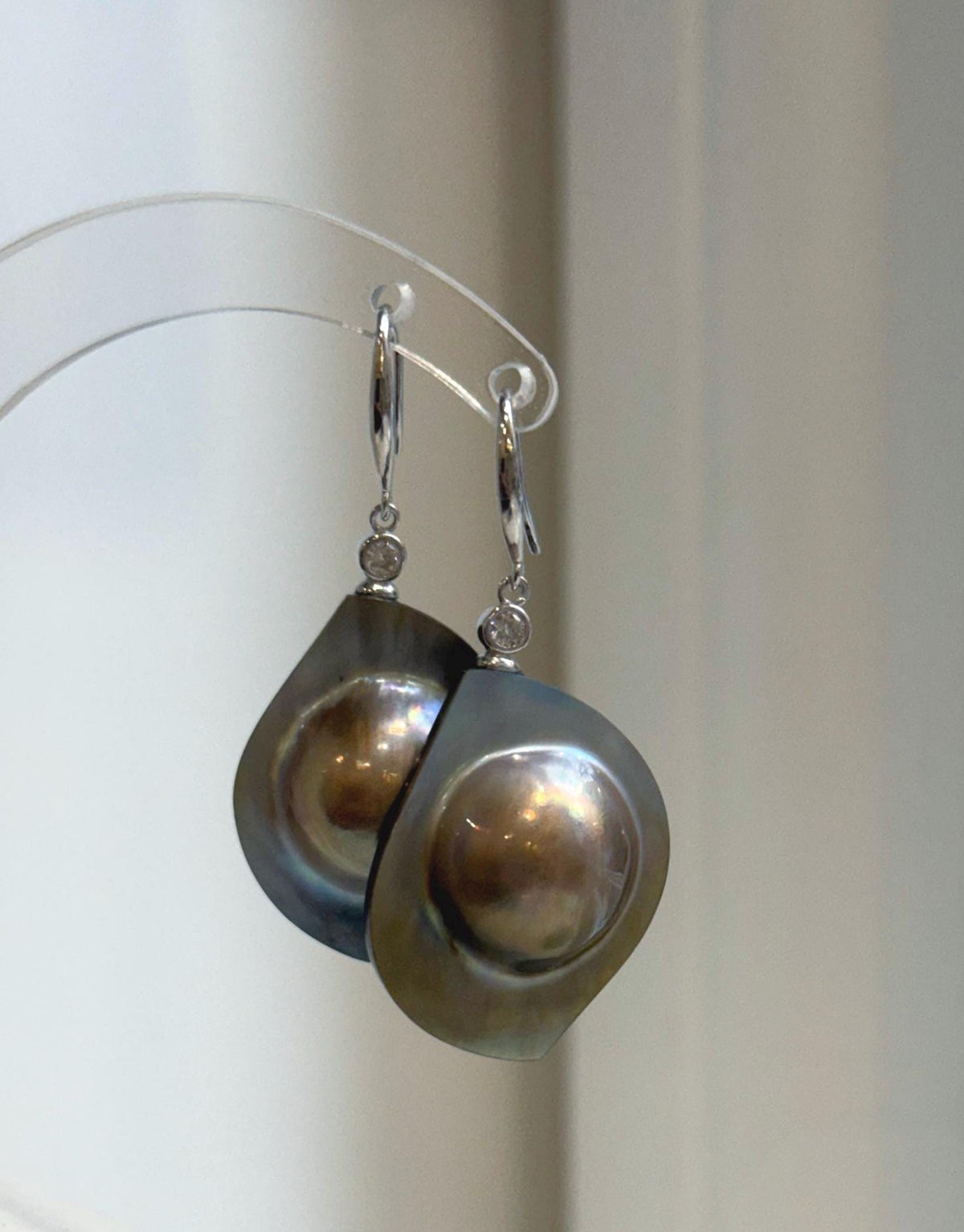 Lustrous golden mabe pearl earrings with shifting rainbow hues.