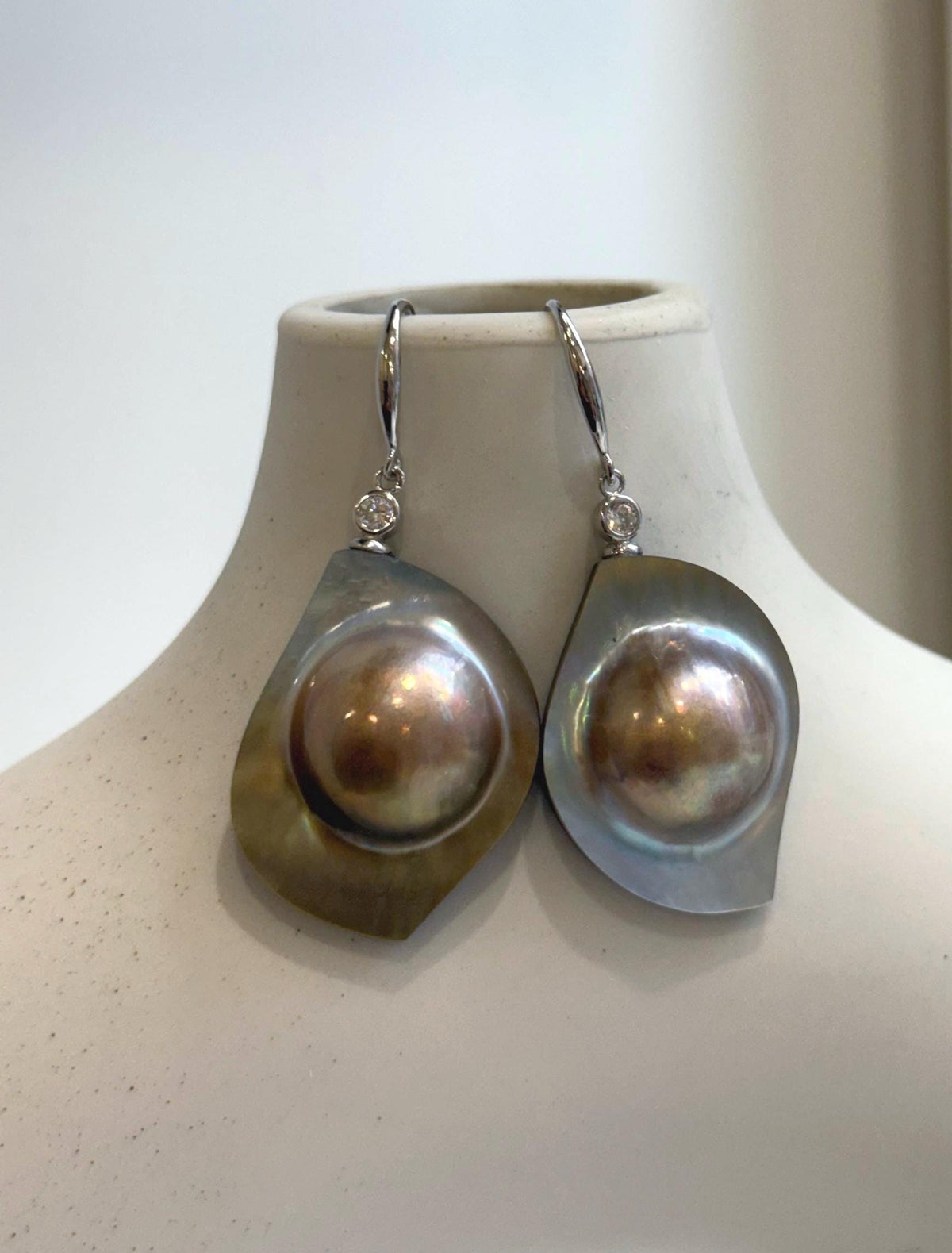 Golden mabe pearl drop earrings with vivid rainbow iridescence.