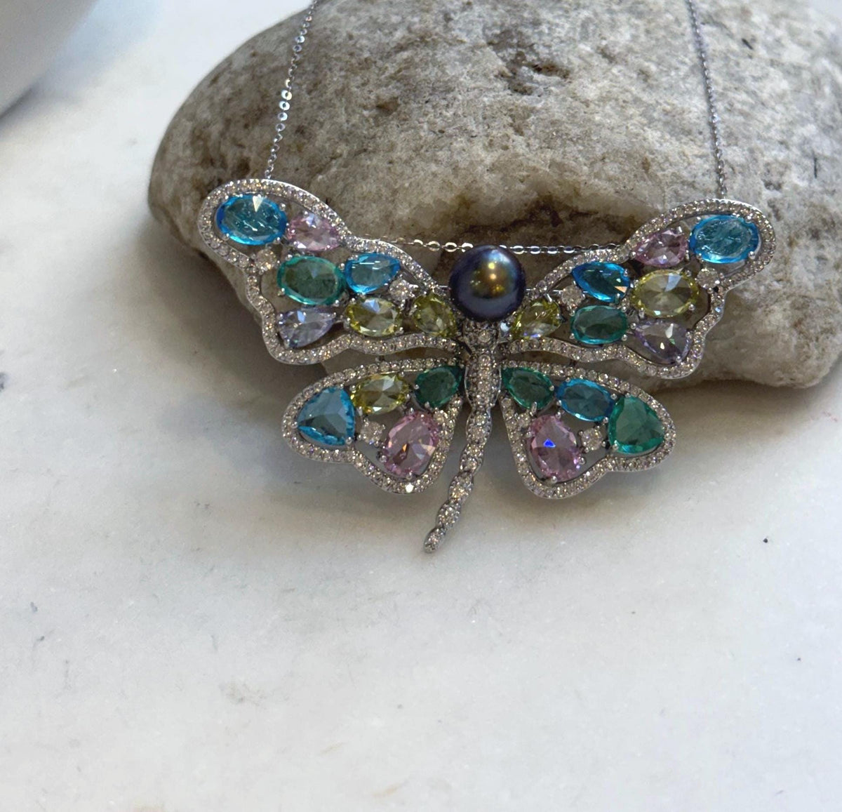 Multicolor sparkling wings surrounding a Tahitian pearl centerpiece.