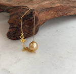 Lustrous golden pearl with delicate chain.