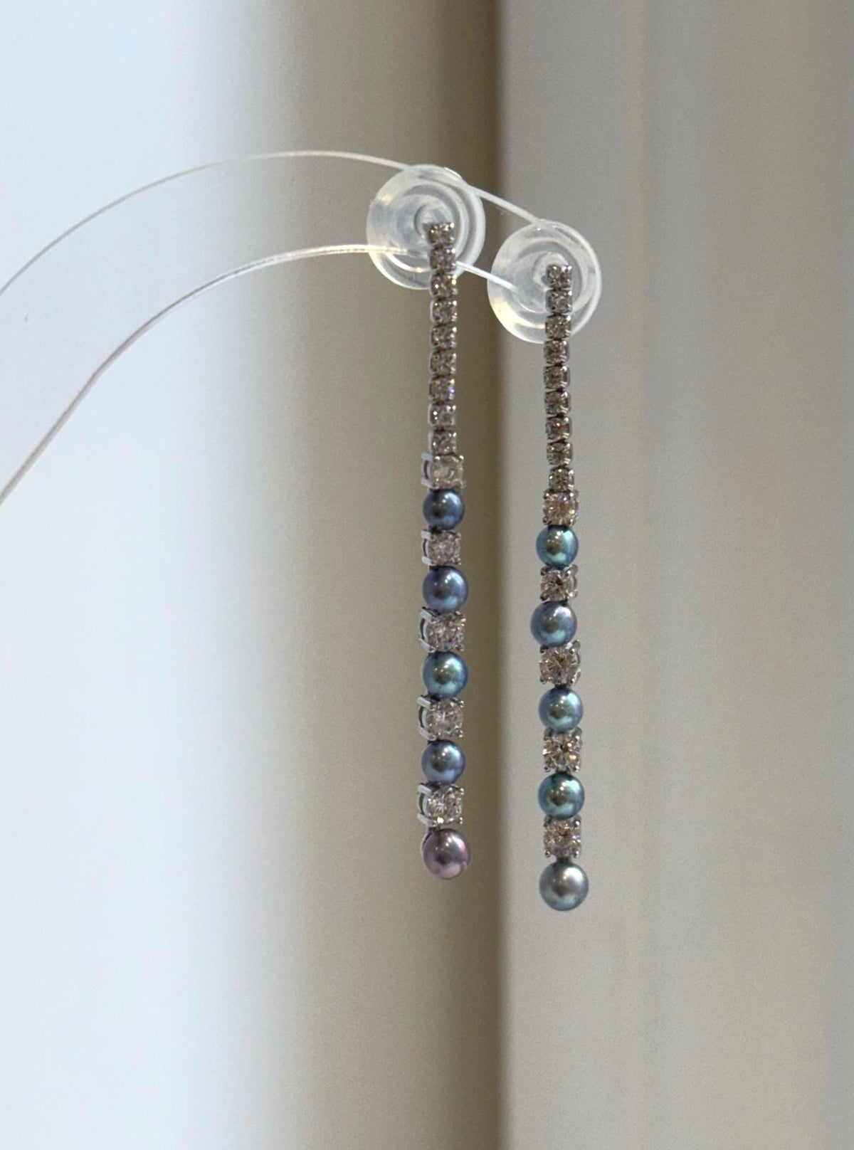 Slender silver drop earrings with peacock-colored pearls.