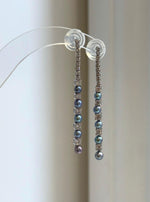 Slender silver drop earrings with peacock-colored pearls.