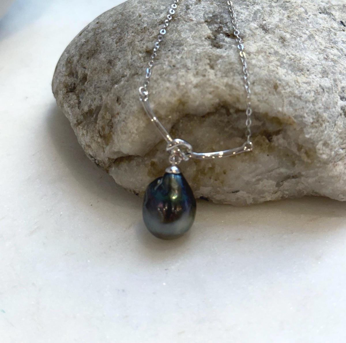 Sterling silver curved bar necklace with a central knot and dangling Tahitian pearl.