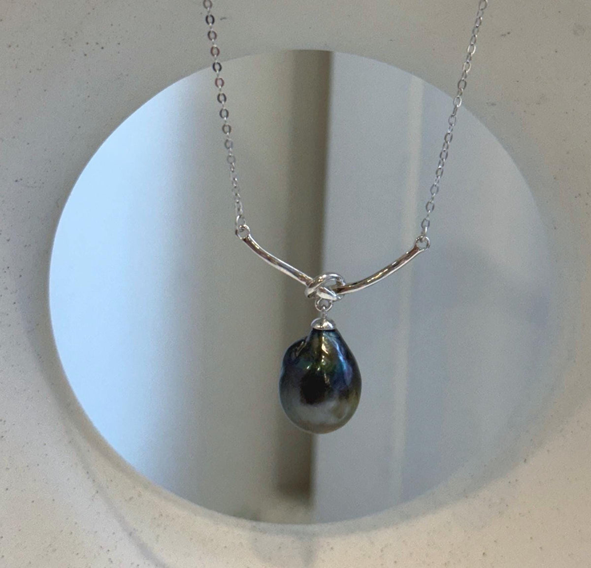 Polished silver knot above a lustrous Tahitian teardrop pearl on a delicate chain.