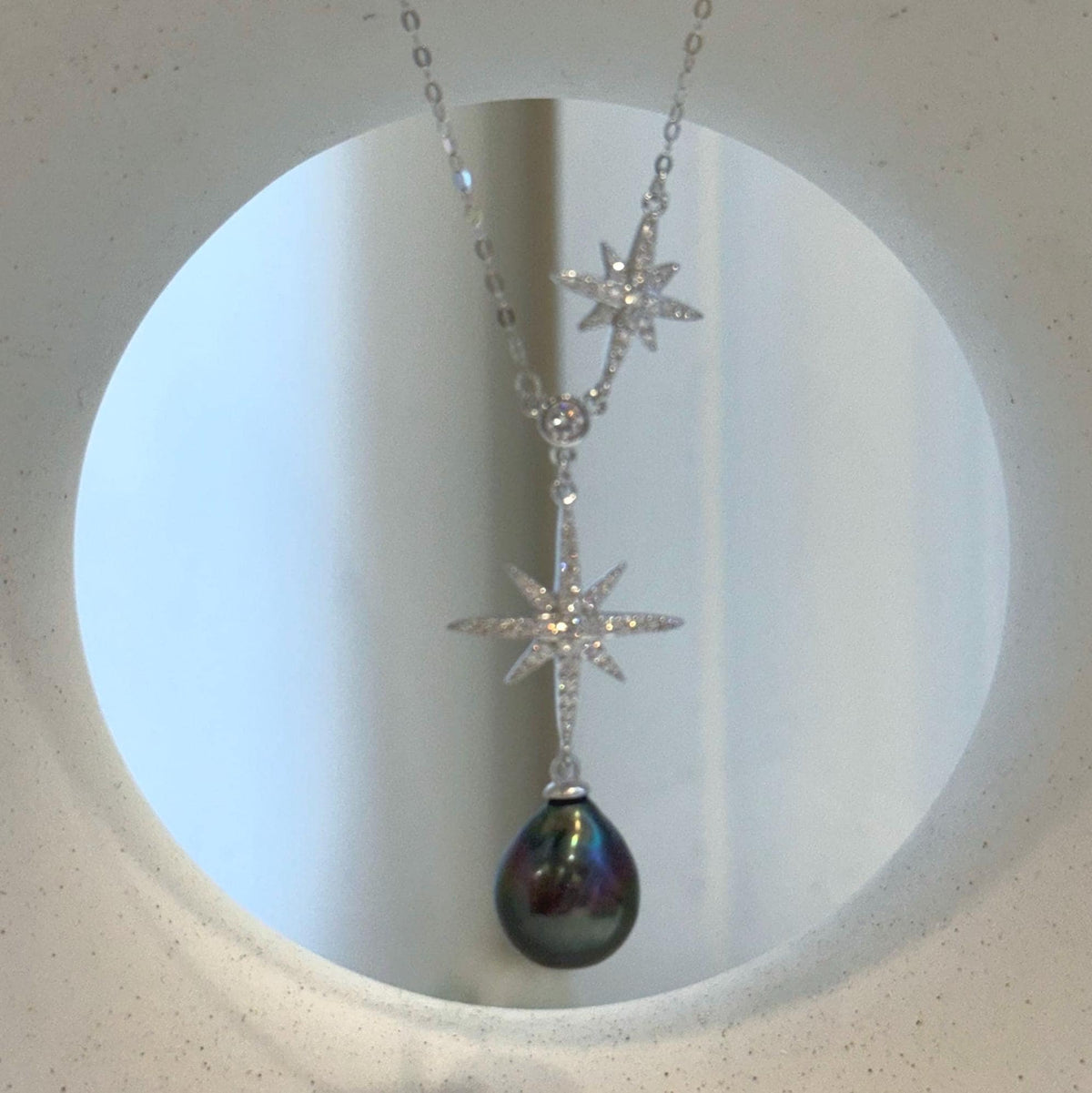 Peacock pearl drop suspended below a crystal-accented eight-point star in sterling silver.