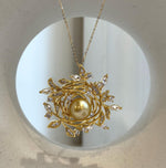 Golden pearl framed by delicate leaves and sparkling stones