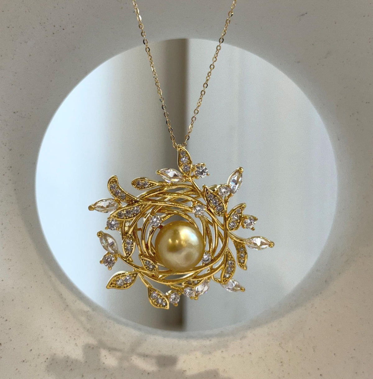 Golden pearl framed by delicate leaves and sparkling stones