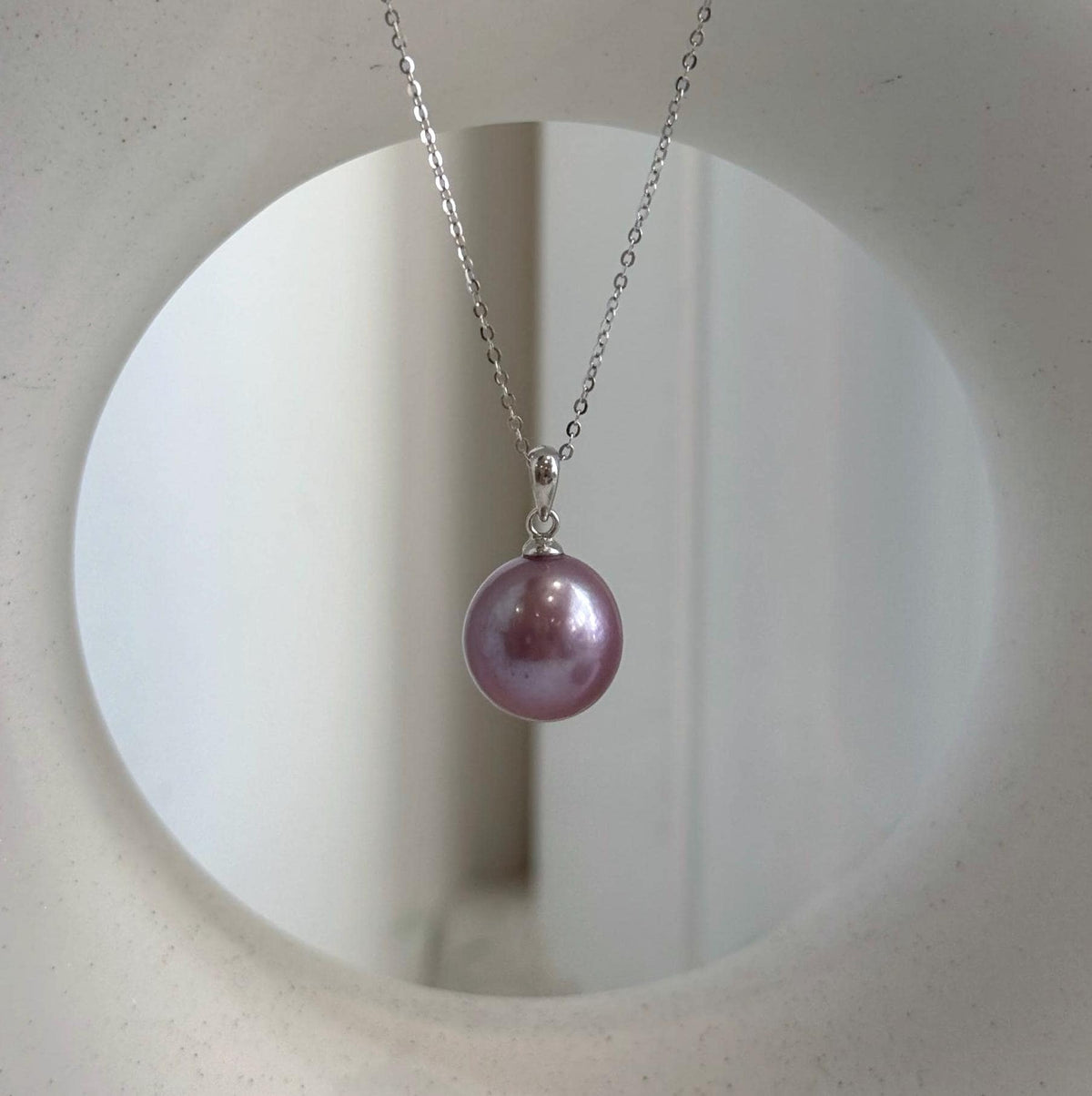 Purple Edison pearl jewelry set displayed beside a textured stone.