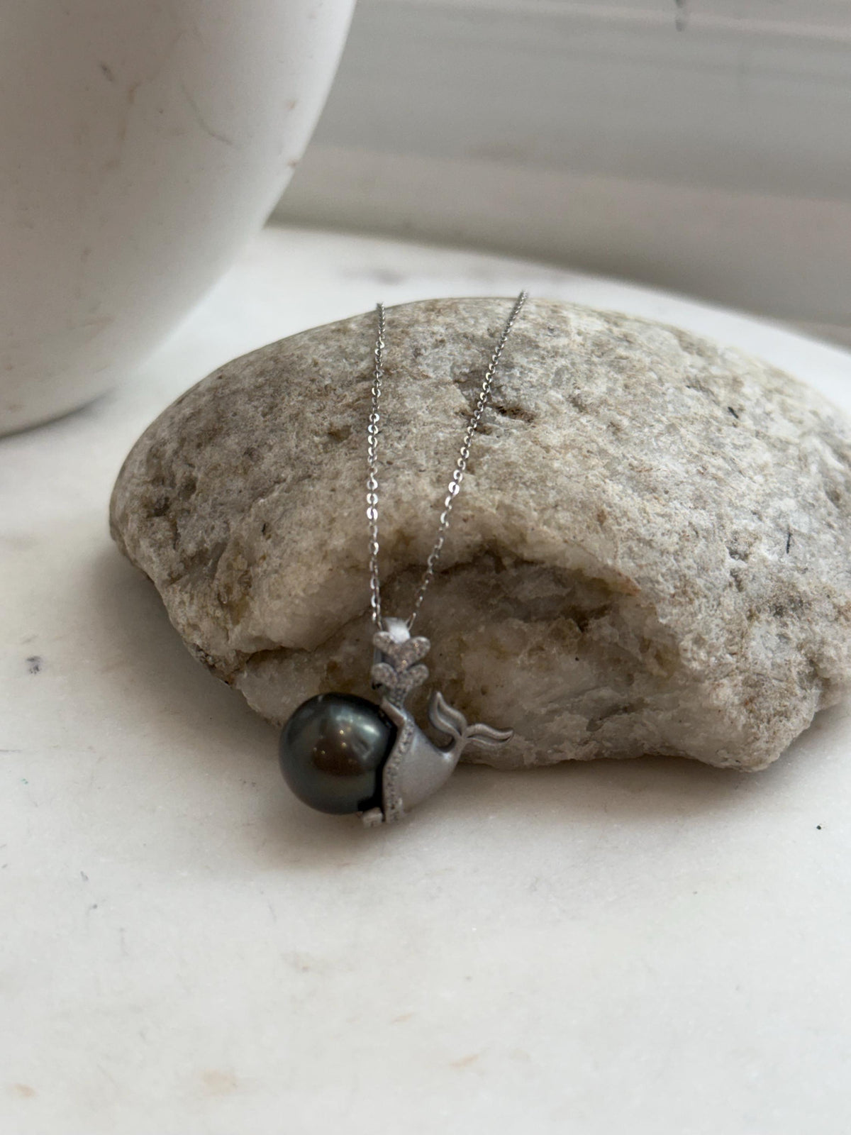 Reflective Tahitian pearl paired with a crystal-accented silver mermaid.