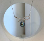 Elegant Tahitian pearl necklace combining a dark green pearl with a sparkling silver bow design.