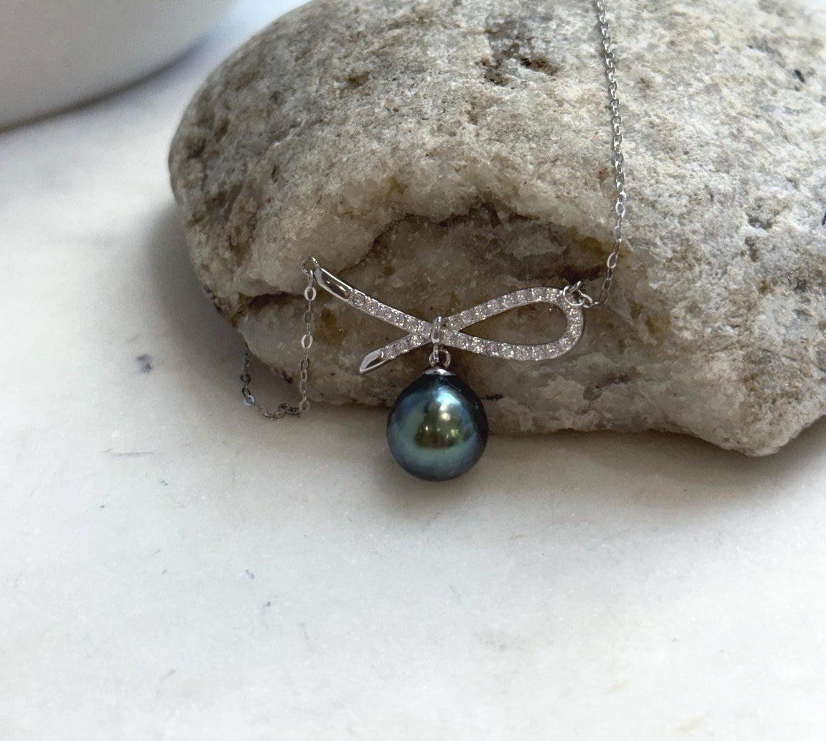 Lustrous Tahitian pearl with green and blue reflections paired with a silver ribbon setting.