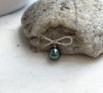 Lustrous Tahitian pearl with green and blue reflections paired with a silver ribbon setting.