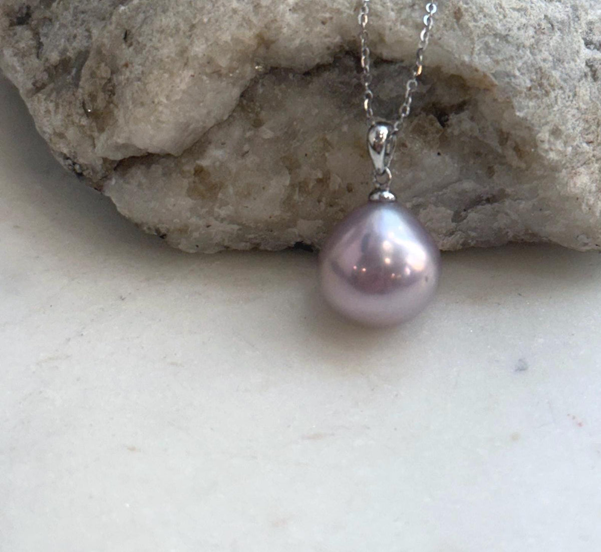 Single teardrop freshwater pearl suspended from a silver chain.