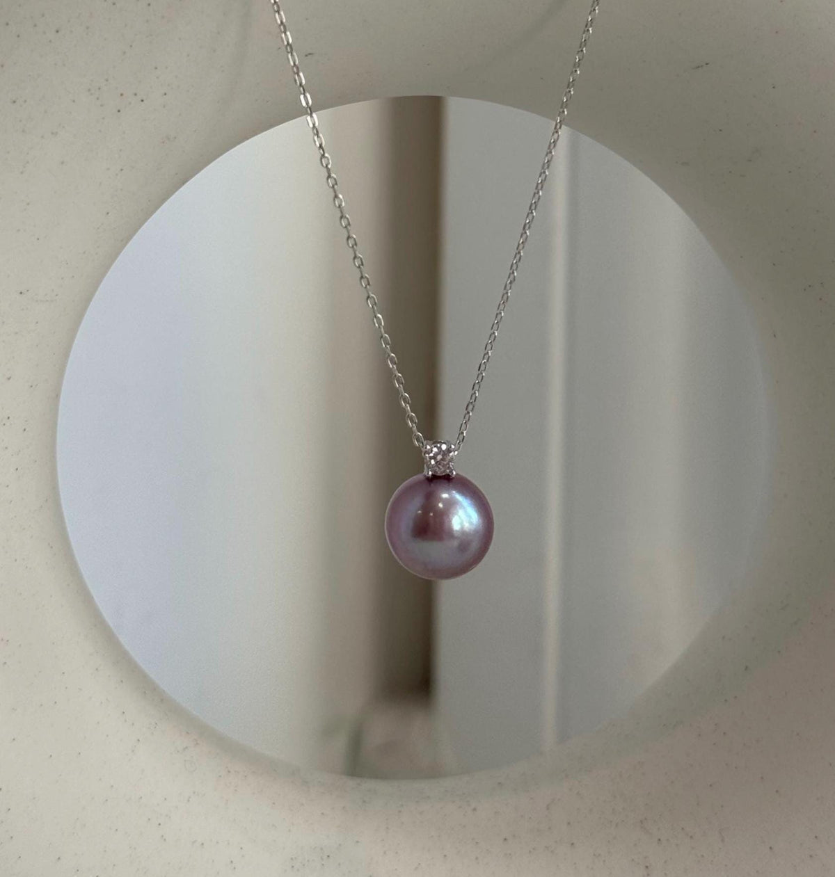 Rose lavender pearl stud earrings with reflective luster.