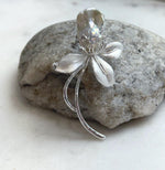 White baroque freshwater pearl brooch with a silver-tone floral design.