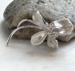 Silver-tone floral brooch featuring an organically shaped freshwater pearl.