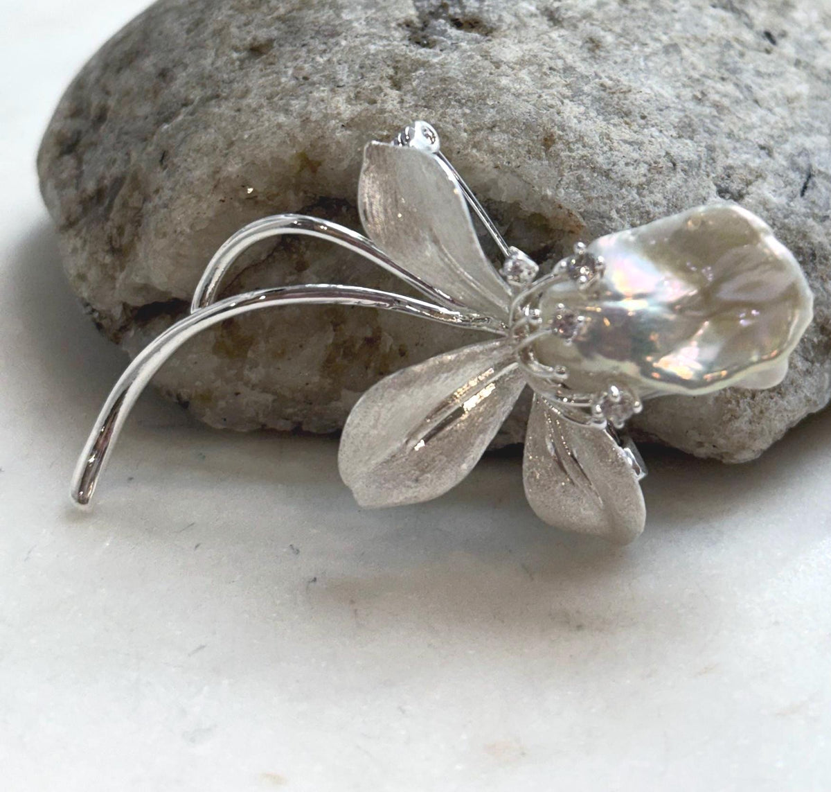 Silver-tone floral brooch featuring an organically shaped freshwater pearl.