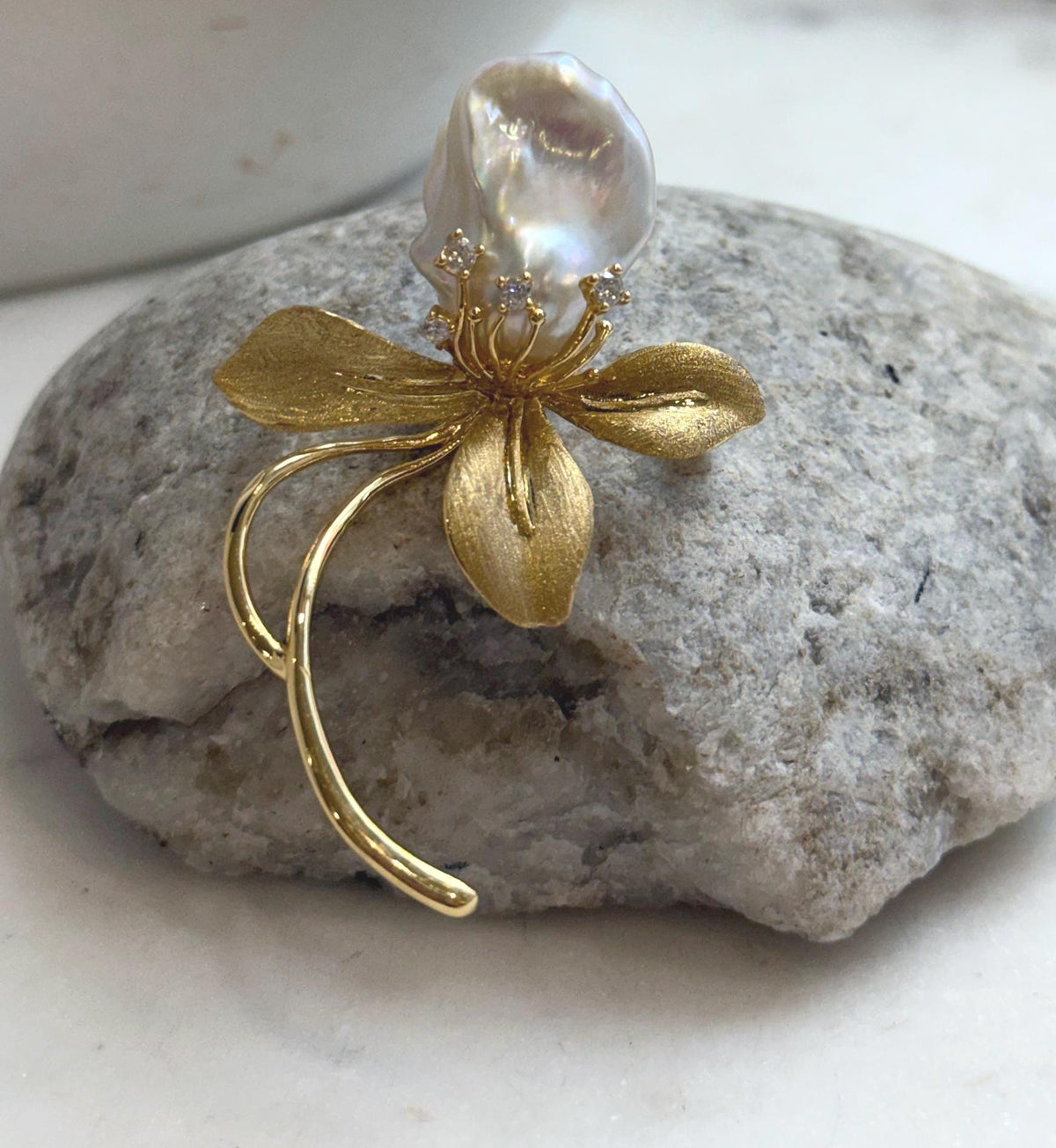Gold-tone floral brooch featuring a lustrous white freshwater pearl.