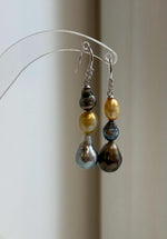 Ocean pearl earrings featuring three lustrous pearls on each silver hook.