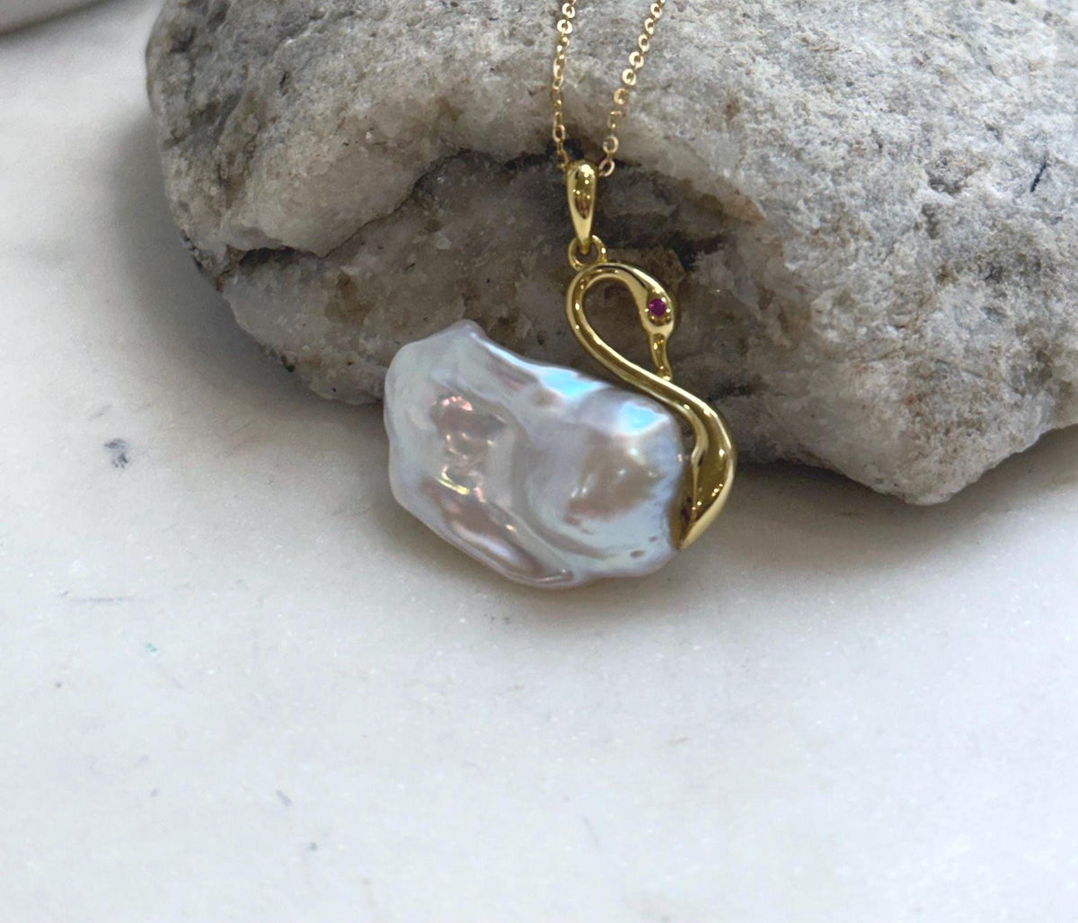Iridescent pearl necklace with a graceful gold-tone swan design.