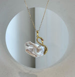 Swan pendant featuring a white baroque pearl body and red eye accent.